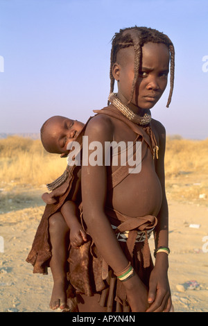 Young Himba girl carries a little child on her back Stock Photo