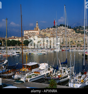 View across the harbour looking through tall yacht masts at quayside in marina at Menton South of France
