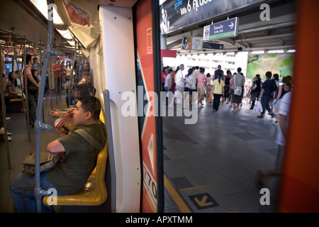 commuters and tourists disembark a Sukhumvit line Skytrain, in Bangkok, Thailand. Stock Photo