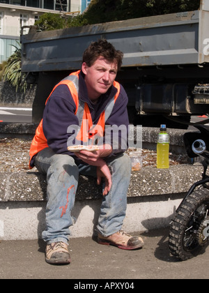 Workman wearing safety jacket eating his lunch with food and drink Stock Photo
