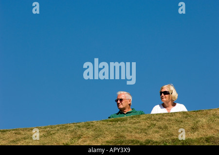 A man and woman, middle aged couple, against blue sky, wearing sunglasses, summer afternoon, Aberystwyth wales UK Stock Photo