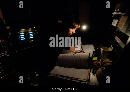 A woman girl female stage manager in a theatre, making notes in her copy of the script of a play in a performance, UK Stock Photo