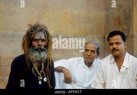 Sadhu sitting next to other Indian men on the banks of a Ghat in Varanasi, India Stock Photo
