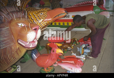 A young man demonstrating and showing coffins urns and caskets at a coffin shop or undertakers in Ngungua near Accra Ghana Stock Photo