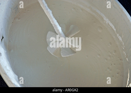 Stirrer in bucket with white paint Stock Photo - Alamy