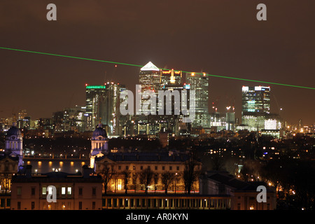 A green laser beam marking the Greenwich Meridian Line  shines at night in front of the Canary Wharf skyscraprs in London Stock Photo