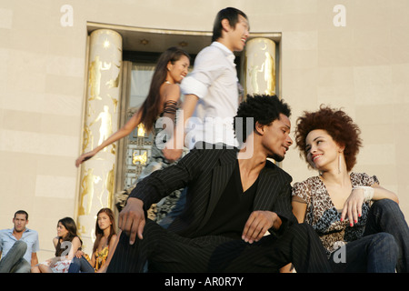 African American couple sitting outdoors, with people behind them Stock Photo