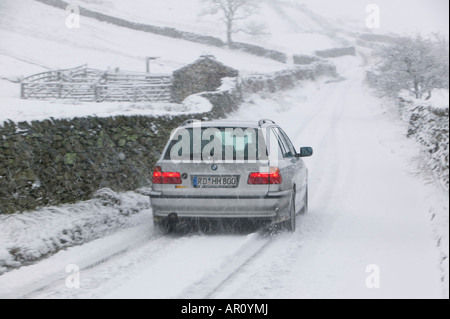 A BMW driving up Kirkstone Pass in the Lake District in heavy snow UK Stock Photo