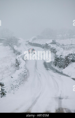 A BMW driving up Kirkstone Pass in the Lake District in heavy snow UK Stock Photo