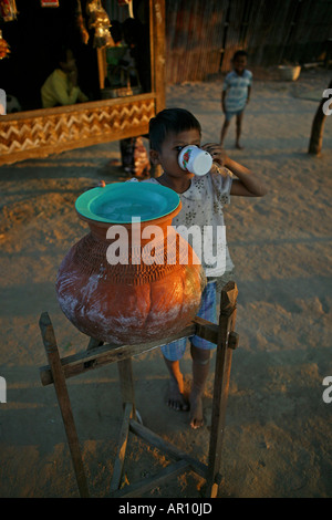 Child drinks water from terracotta pot, Kind trinkt Wasser aus dem Tontopf, Tonkrug, diese Wasserbehaelter stehen ueberall in Bu Stock Photo