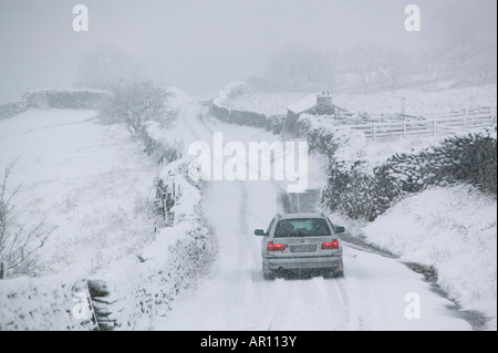 A BMW driving up Kirkstone Pass in the Lake District in heavy snow UK Stock Photo