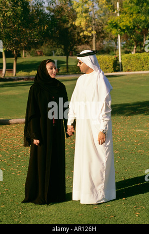 An Arab couple smiling at each other as they hold hands in the park. Stock Photo