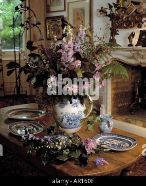 Still-Life of mauve and pale blue delphiniums with foliage in vase on antique table with blue+white china Stock Photo