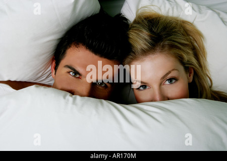 Young couple under the covers in bed. Stock Photo