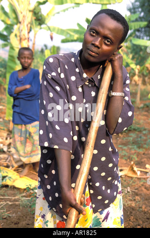 Rwandan genocide orphan Eugenia is mother father to her younger siblings works in fields walks 8km per day to get water Stock Photo