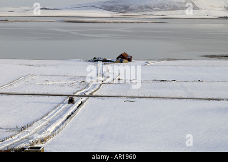 dh  FIRTH ORKNEY White snow fields tractor on road and farm roads snowy track house field winter landscape scotland uk distance Stock Photo