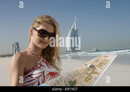 Young lady with Dubai map in front of the famous landmark of Dubai Stock Photo