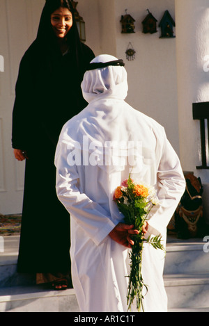 Rear view of a husband hiding the bouquet from his wife. Stock Photo