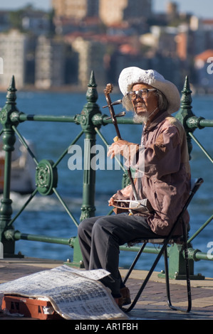 Elderly Chinese man playing an old Chinese string instrument, the erhu, on the street, busking. Stock Photo