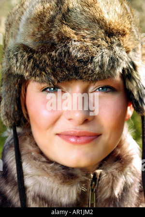 outdoor autumn day mead field grass close up woman young 25 30 portrait jacket fur cap smile smiling vertical Stock Photo