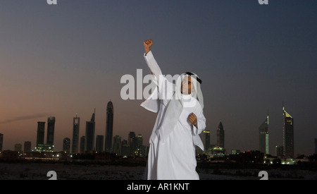 Young Arab man jumping with joy with Dubai City in the background Stock Photo