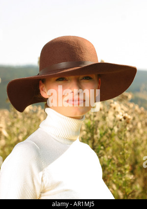 outdoor autumn day mead field grass close up woman young 25 30 portrait sweater golf jersey white hat brown smile smiling ver Stock Photo