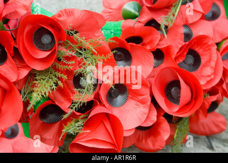Horizontal close up of a wreath of artificial bright red poppies laid at a monument for Rememberance Day. Stock Photo
