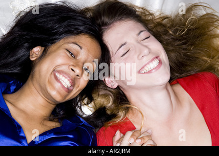 two girlfriends, a light-skinned and a dark-skinned woman laughing Stock Photo