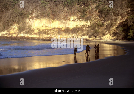 Golden wet sand at dusk (2). Sun worshippers strolling along beach of  Baia dos Golfinhos, near Pipa, Natal, NE Brazil. Stock Photo