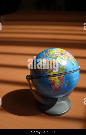 Globe on desktop with shadows from vertical blinds Stock Photo