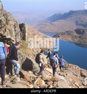 Rear view of a group of walkers walking hiking down on trail descending from Mount Snowdon with a view of Glaslyn Lake North Wales UK    KATHY DEWITT Stock Photo