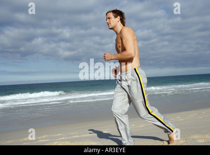 Young man jogging along beach Stock Photo