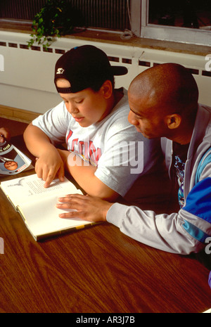 African American teacher and student age 28 and 10 in after school reading program. St Paul Minnesota USA Stock Photo
