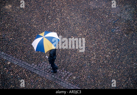 Man walking in rain with umbrella Stock Photo