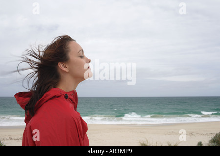 Young woman wearing red raincoat on beach Stock Photo