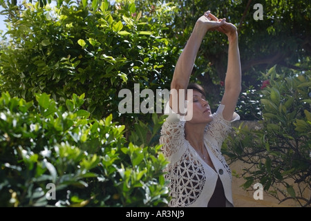 Mature woman performing stretching exercises outdoors Stock Photo