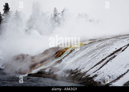 Yellowstone National Park in winter snow frost covered rock trees on Firehole River at Excelsior Spring Stock Photo