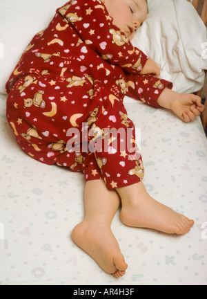 Young boy wearing pyjamas sleeping in cot Stock Photo