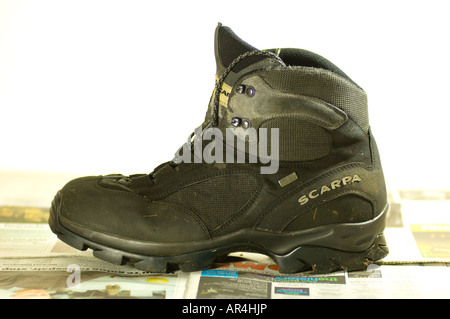 Dirty walking boot drying out on newspaper Stock Photo