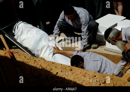 Orthodox Jewish pallbearers lower the body of renowned Nazi-hunter Simon Wiesenthal into a grave at his funeral in the town of Herzliya in Israel Stock Photo