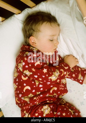 Young boy wearing pyjamas sleeping in cot Stock Photo