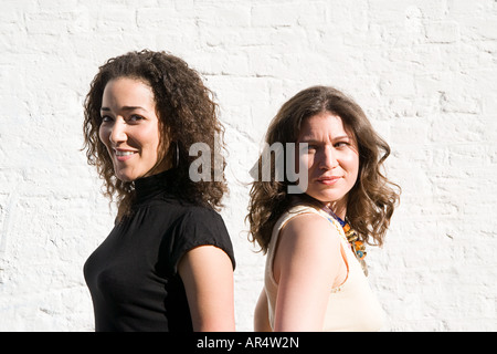 Two young women standing back to back, white background Stock Photo - Alamy