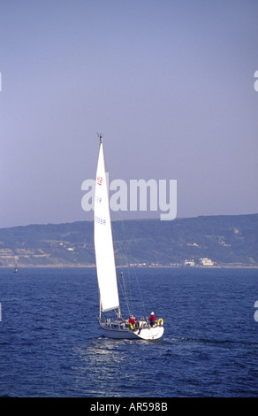 Yacht Sailing off Hurst Point with the Isle of Wight in the distance Milford on Sea Hampshire England UK Stock Photo