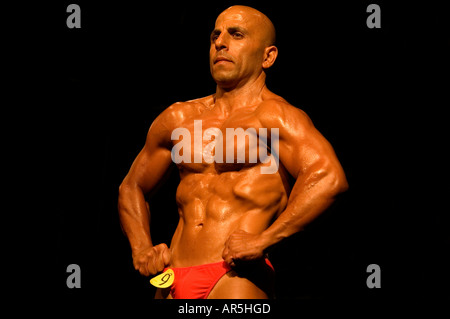 Bodybuilder performing a most muscular pose in gym stock photo