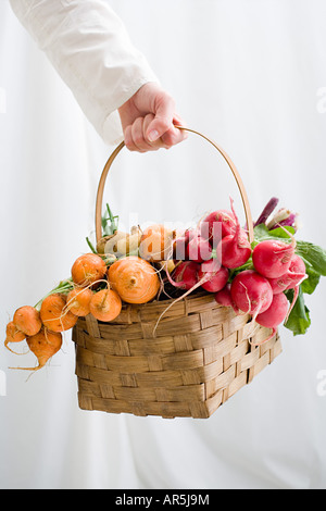 Woman holding basket of beetroot and radishes Stock Photo