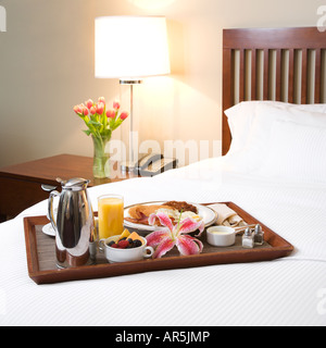 Breakfast tray laying on white bed in upscale hotel Stock Photo