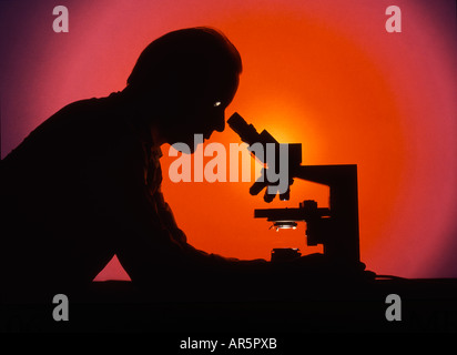 Lab technician looking through microscope Stock Photo
