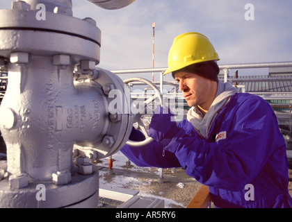 Oil industry worker turning valve at refinery. Stock Photo