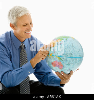 Middle aged Caucasian man pointing on globe Stock Photo