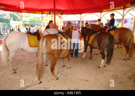 Children horse riding in tent Gaubodenfest in Straubing Bavaria Germany Stock Photo